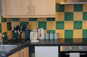 Una cucina con zoccolo paraschizzi a scacchi, lavello, tostapane e frigorifero.