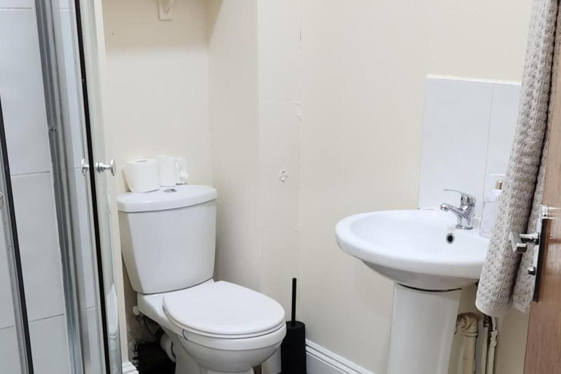 A small, clean bathroom with a toilet, sink, and a towel hanging on the door.