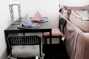Una camera da letto piccola e ordinata, con un letto, una sedia, un tavolo con una lampada e un comodino con una bottiglia.