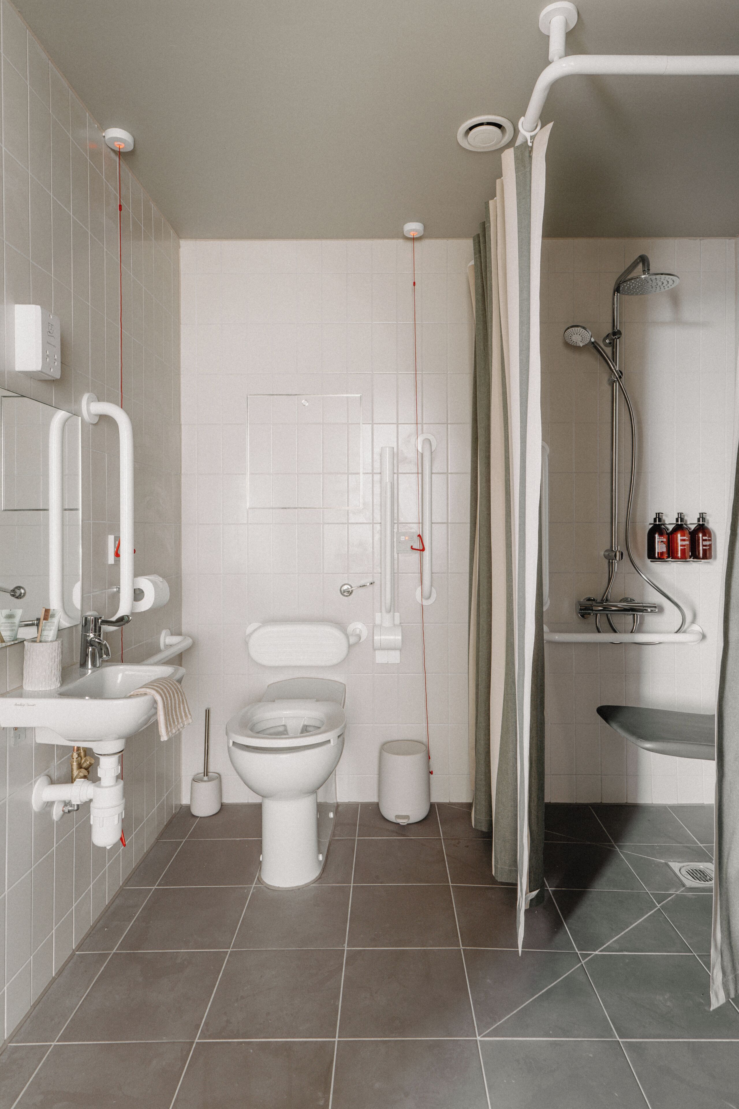 A modern bathroom with a toilet, sink, shower, and storage cabinets.