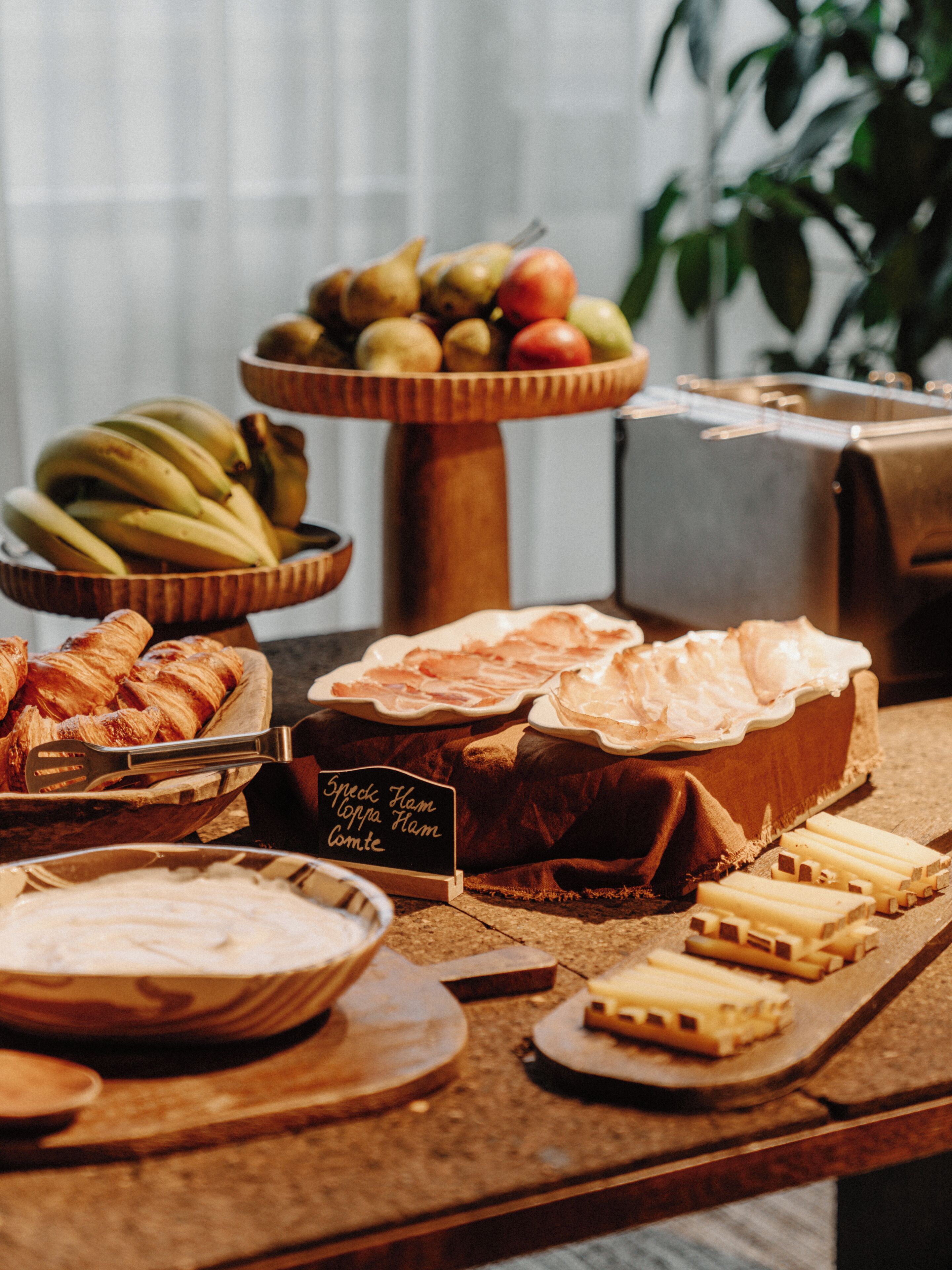 A buffet table with various food items including fruits, pastries, and cheese.