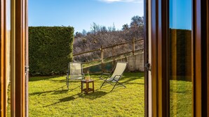 A view through a glass door of a backyard with a lawn, a wooden fence, and a chair. - Rifugio Marley in Pescocostanzo (Pescocostanzo)