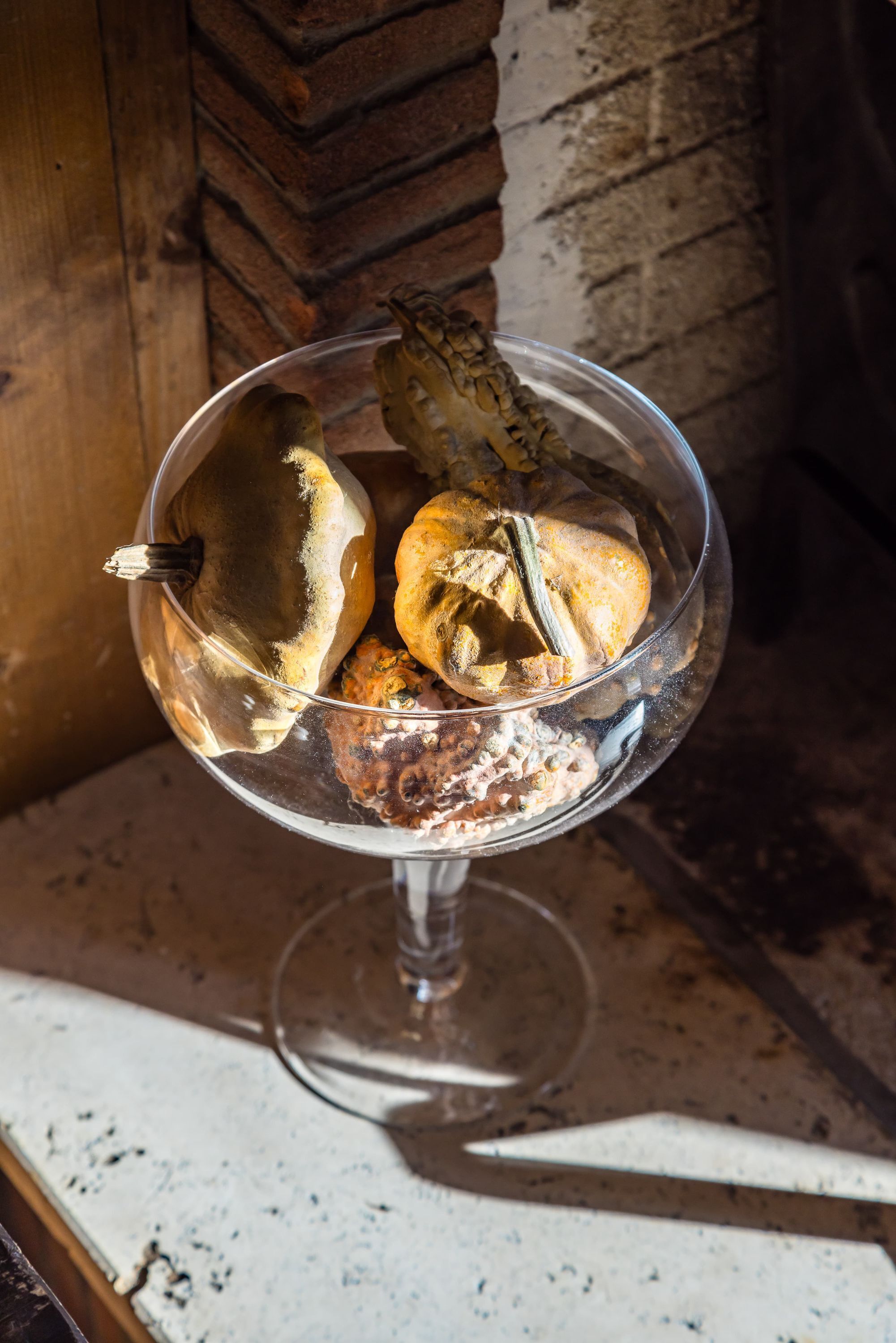 A glass bowl containing various dried mushrooms on a wooden surface.
