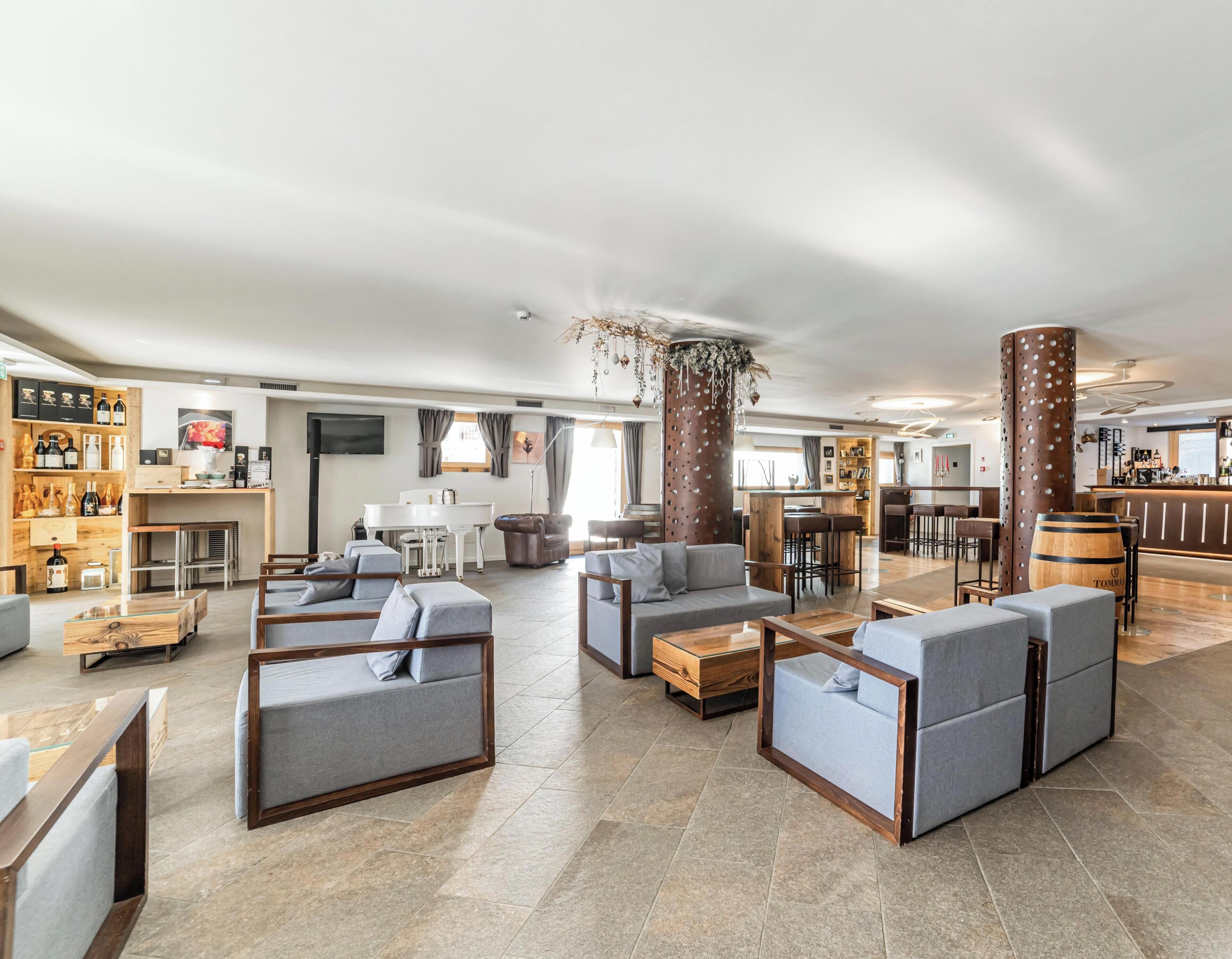 Eine geräumige Lobby mit Sitzbereichen, einem Klavier und einer Bar.