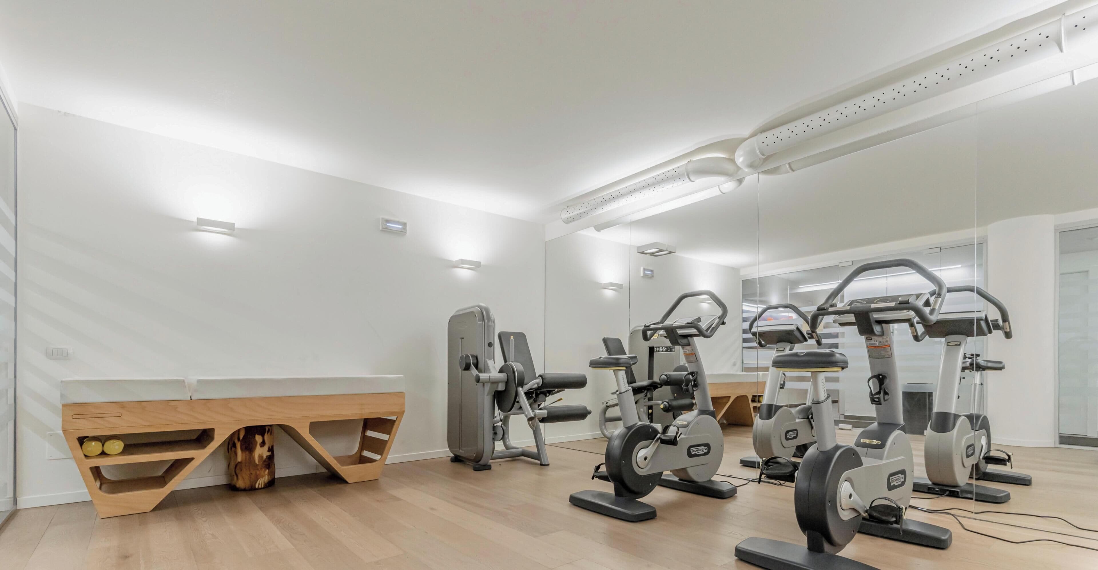 Ein Fitnessraum mit Trainingsgeräten, Holzböden und weißen Wänden.