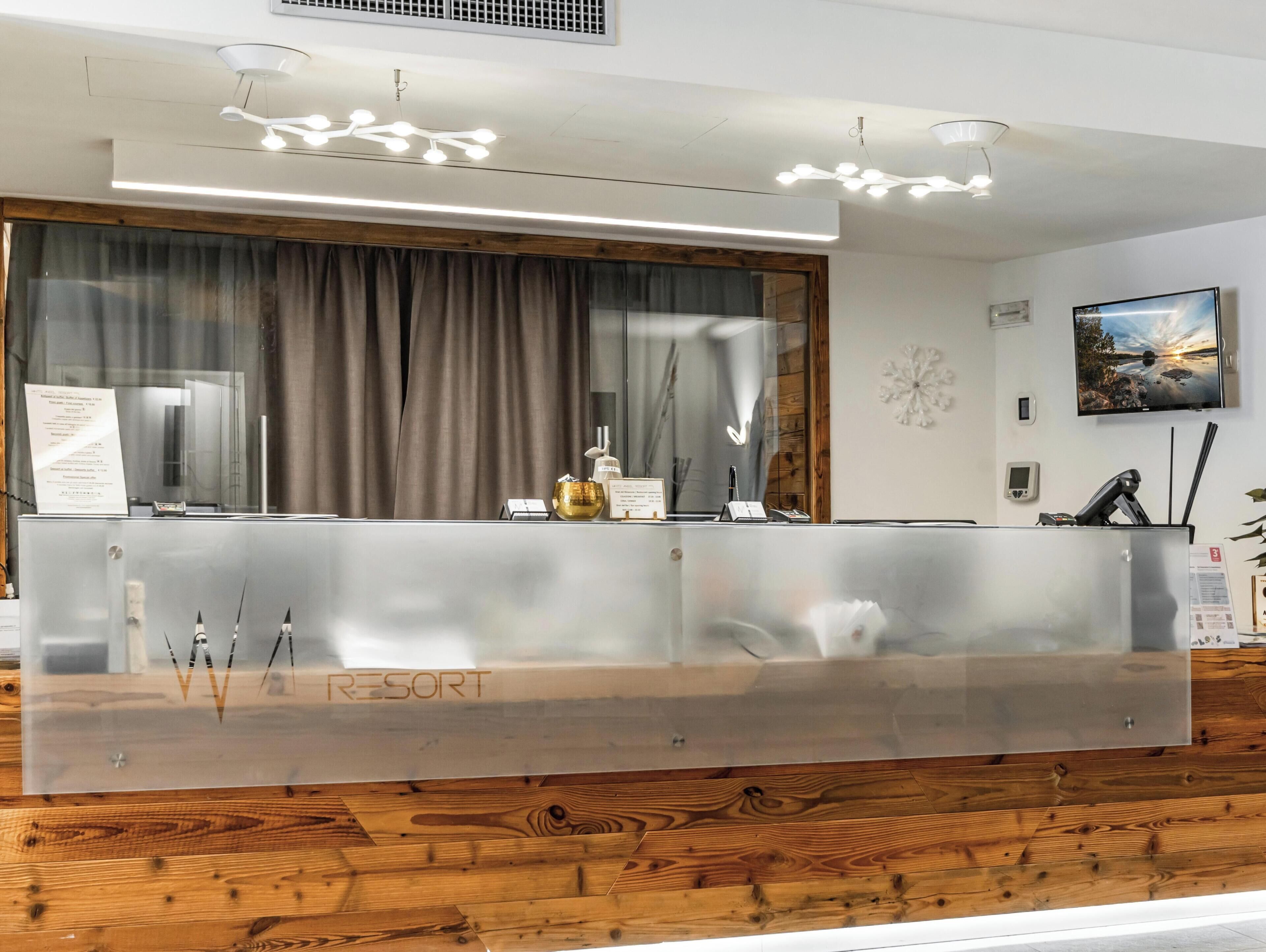 A reception desk with a wooden panel backdrop, a mounted television, and a wall-mounted thermostat.