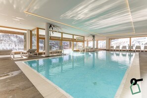 Una piscina techada, sillones reclinables de piscina