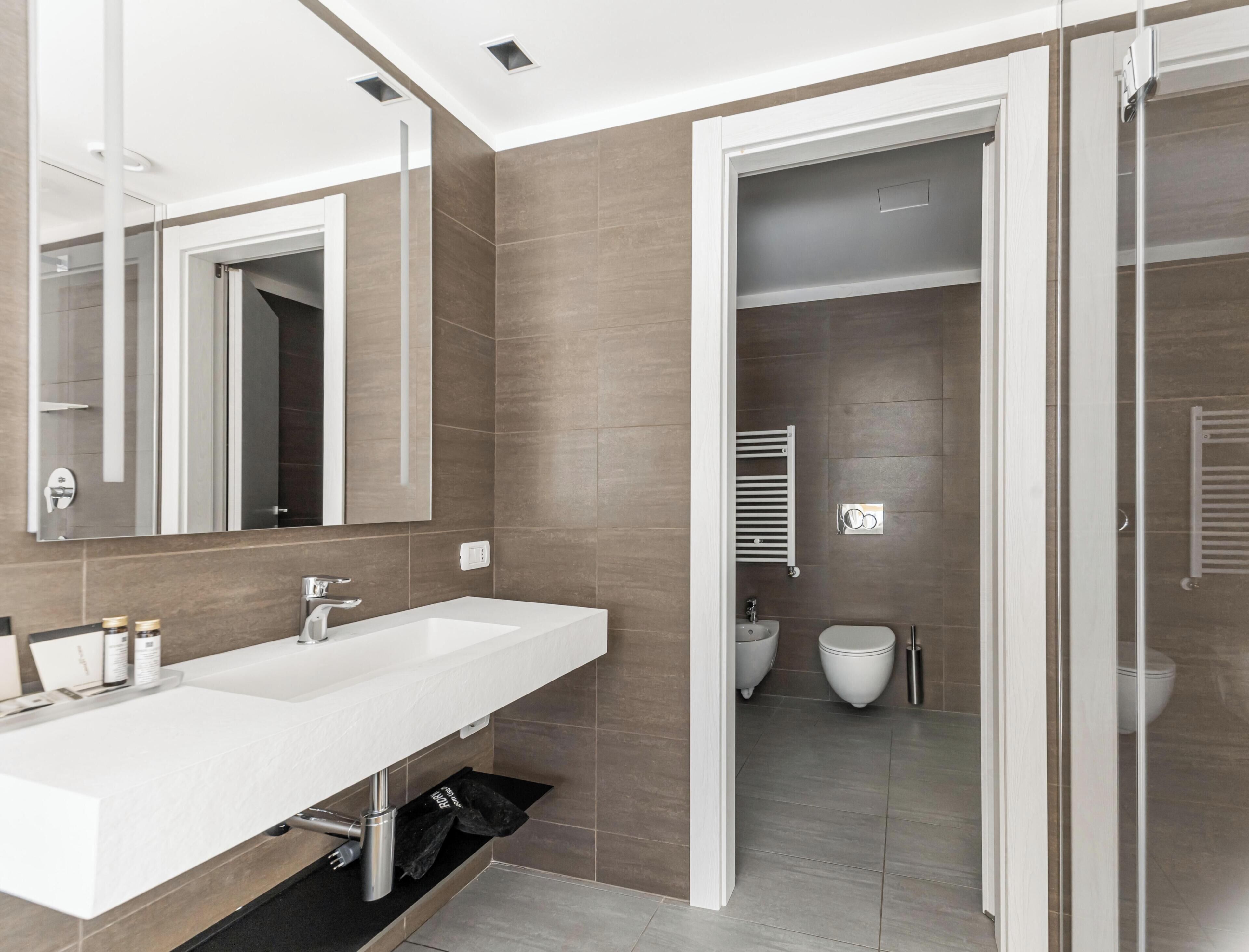 Une salle de bain moderne avec un meuble-lavabo à deux vasques, un miroir, un porte-serviettes et des toilettes.