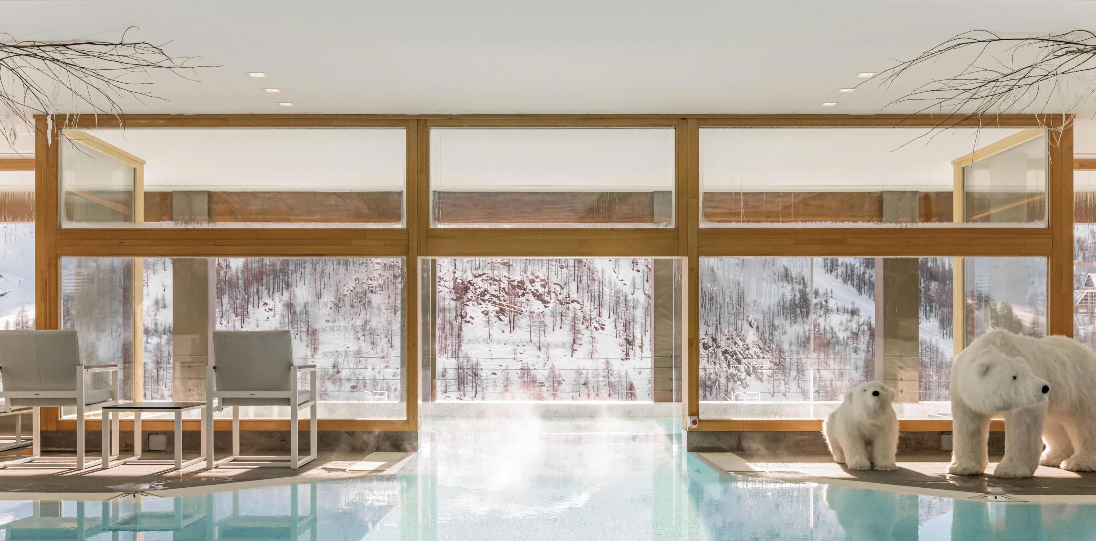 Área da piscina com vista para árvores nevadas através de grandes janelas.