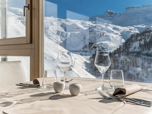 A dining table set with glasses and cutlery, overlooking a snowy mountain landscape. -  Hotiday Cervinia Ski&Spa (Valtournenche)