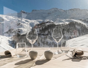 A table set with wine glasses and cutlery, overlooking a snowy mountain landscape. -  Hotiday Cervinia Ski&Spa (Valtournenche)