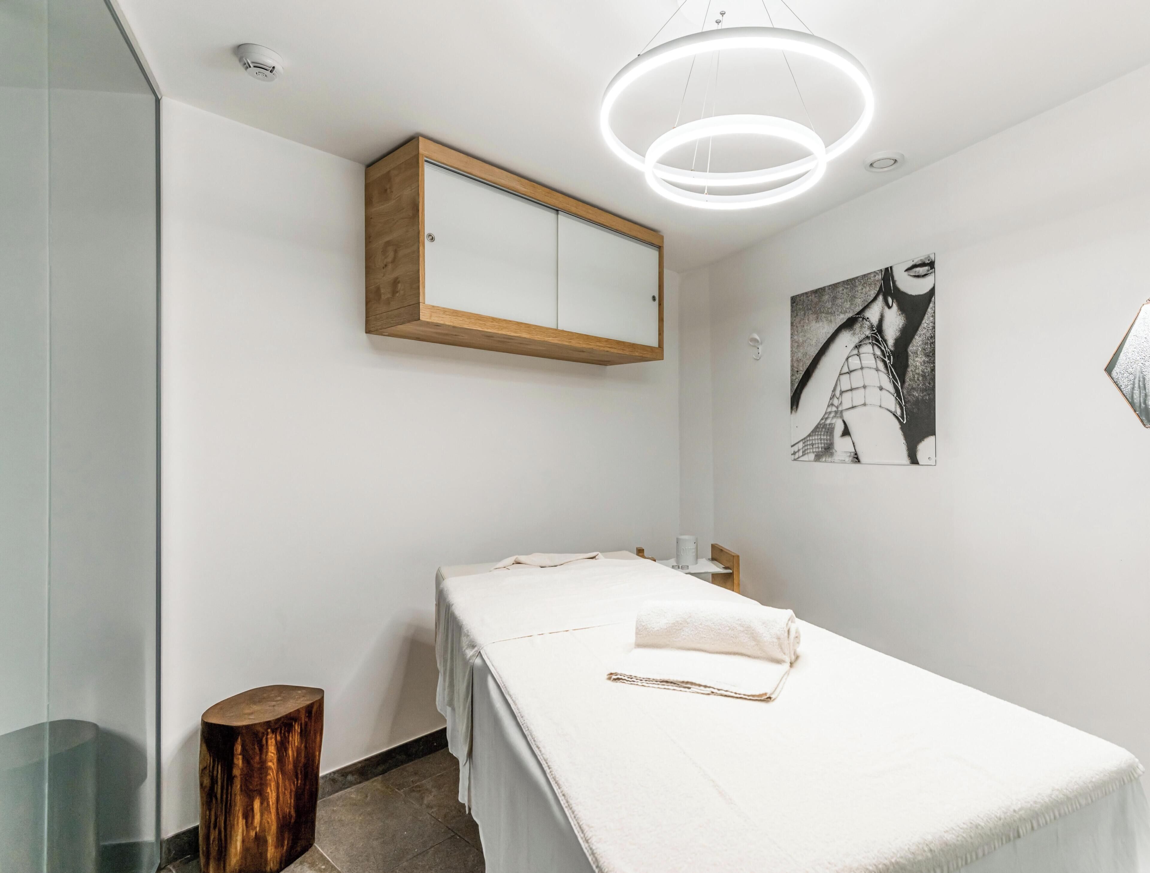 Una camera da letto minimalista con un letto, un armadietto in legno e una lampada moderna.