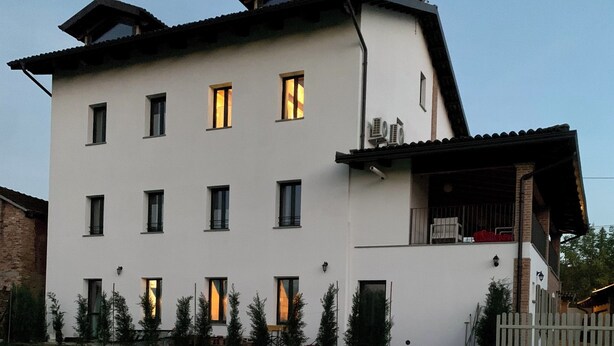 A two-story building with a swimming pool in the foreground. - Cascina 1909 (Priocca)