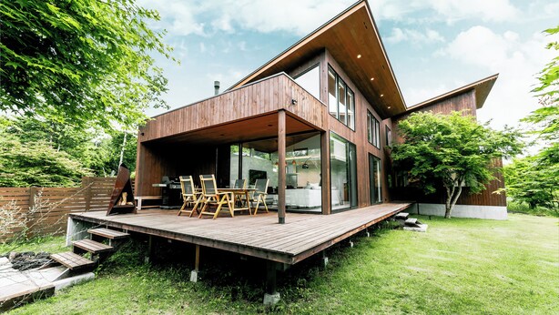 Una casa moderna con terraza de madera, ventanas amplias y un área exterior espaciosa.