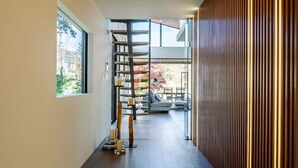 Un pasillo moderno con piso de madera, una ventana y vistas a un balcón.