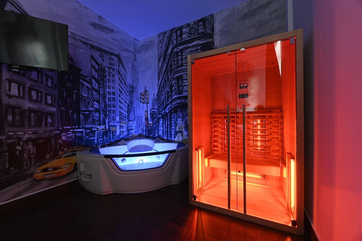 A room with a large mural of a cityscape, a glass-enclosed sauna, and a modern design.