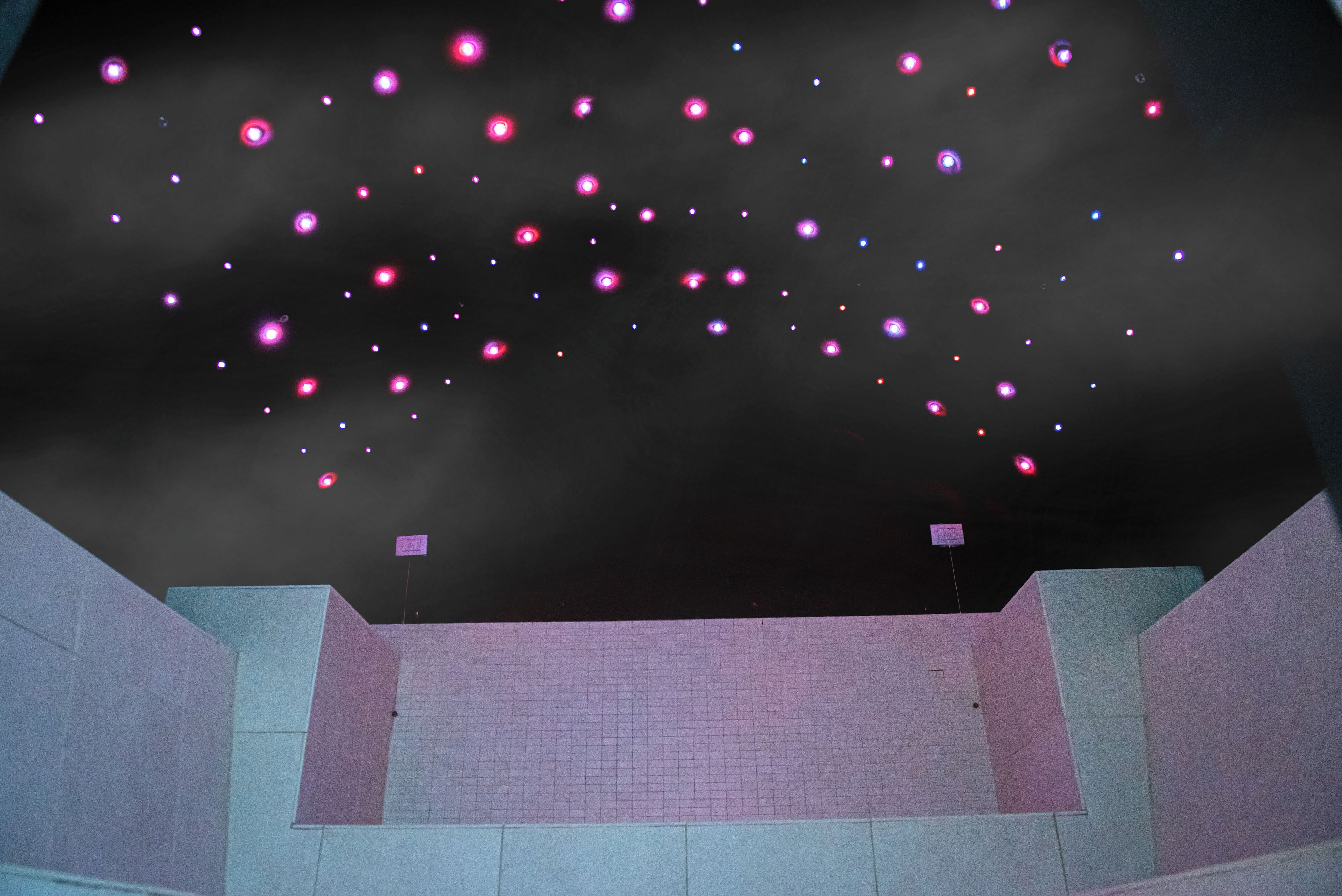 A room with a tiled floor and a dark ceiling with floating lights.