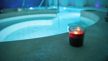A candle on a concrete surface near a pool with a curved edge.