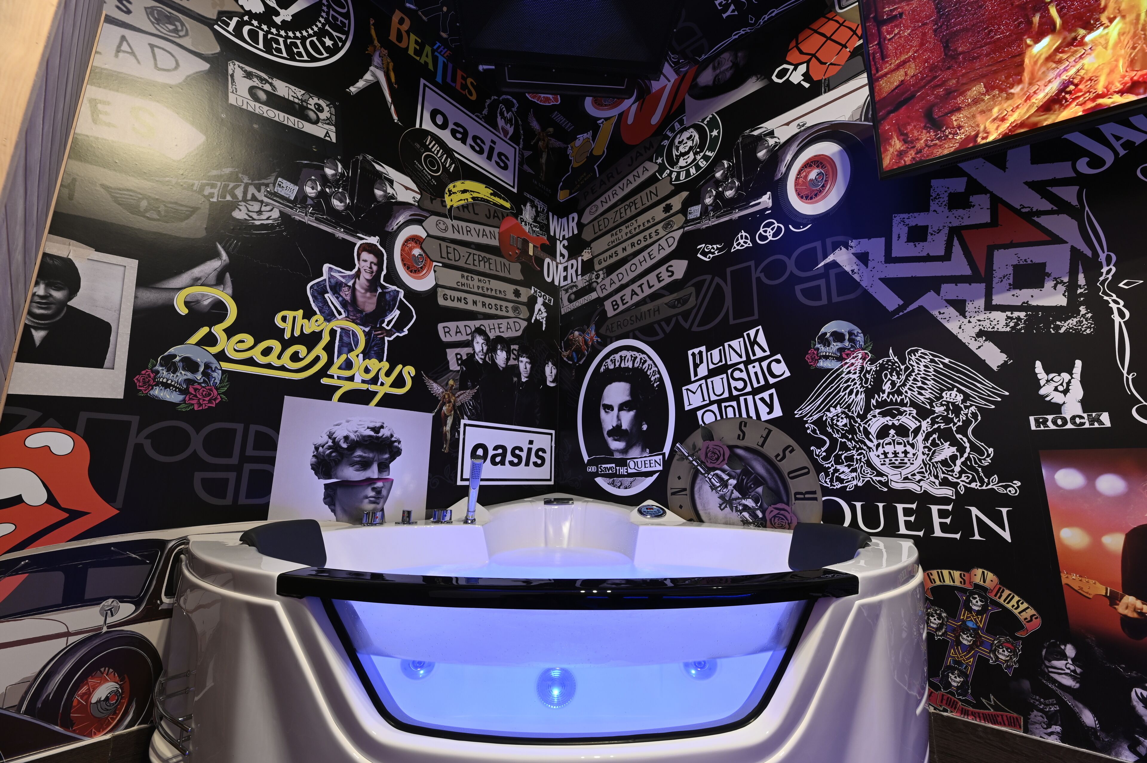 Un baño con una bañera blanca, rodeado de paredes decoradas con pegatinas de bandas y discos de música.