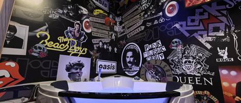 Un baño con una bañera blanca, rodeado de paredes decoradas con pegatinas de bandas y discos de música.