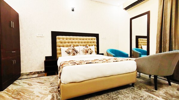 A hotel room with a large bed, a chair, a wardrobe, and a mirror.