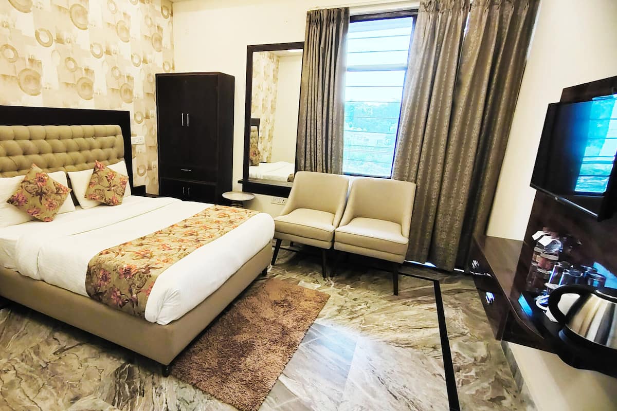 A hotel room with a large bed, a sofa, a TV, and a mirror.