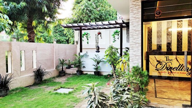 Een binnenplaats met potplanten, een pergola en een gebouw met een bord waarop 