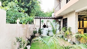 Een modern huis met een tuin, een pergola en diverse planten.