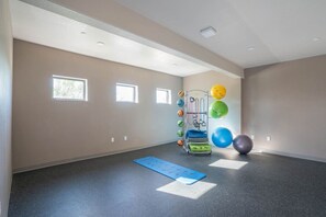 Quarto amplo com carpete cinza, equipamento de exercícios e um tapete azul.