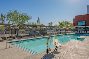 Piscina com cerca de segurança, espreguiçadeiras e área coberta.