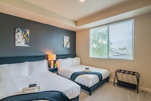 A hotel room with two beds, a nightstand with a lamp, artwork on the wall, and a window with blinds. - Group-Friendly Apt with Pool,Gym,Parking,WD,Balcon (Tempe)