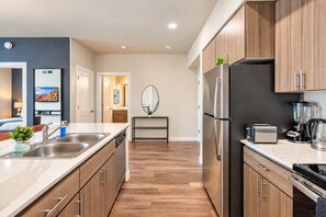 Una cocina moderna con armarios de madera, electrodomésticos de acero inoxidable y una encimera de mármol.