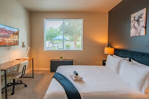 A hotel room with a bed, desk, chair, lamp, and artwork on the walls. - Prime Location with Balcony, Pool, Gym, WD, Parkin (Tempe)