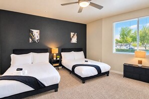 A hotel room with two beds, a ceiling fan, artwork on the walls, and a window with a view. - Prime Location with Balcony, Pool, Gym, WD, Parkin (Tempe)