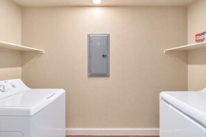 A laundry room with two white washing machines, a grey utility cabinet, and beige walls.