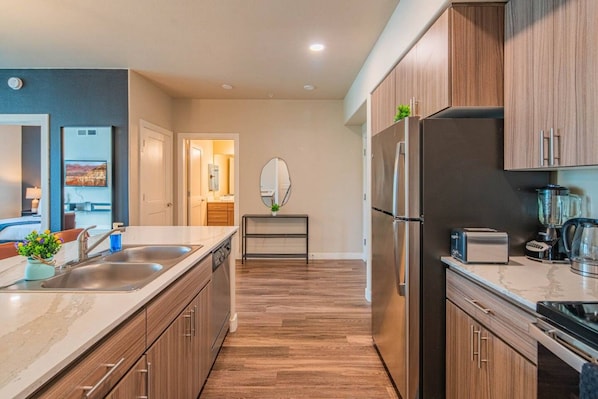 A modern kitchen with wooden cabinets, stainless steel appliances, and a marble countertop.