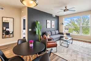 A modern living room with a sofa, coffee table, and dining area. - Family-Friendly Apt | Pool,Gym,W/D,Parking,Balcony (Tempe)