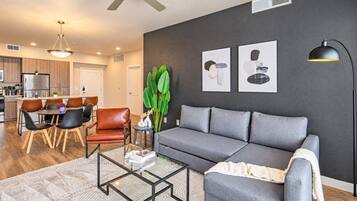 Ein modernes Wohnzimmer mit einem grauen Sofa, einem Couchtisch und einem Essbereich mit Stühlen und einem Tisch.