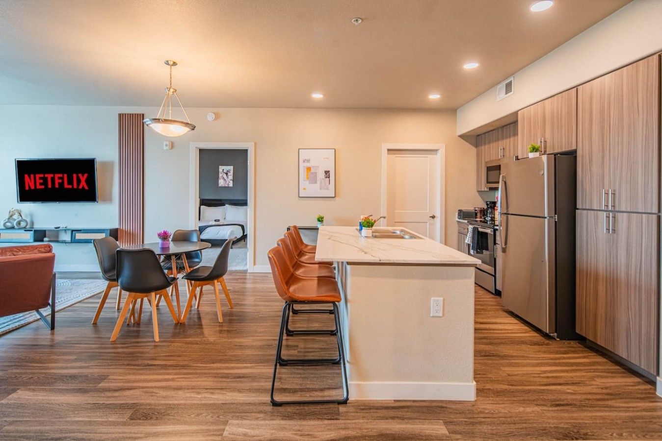 Une cuisine moderne avec des meubles en bois, un îlot central et un coin repas comprenant des chaises et une table.