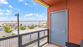 A balcony with a view of a parking lot and industrial buildings.