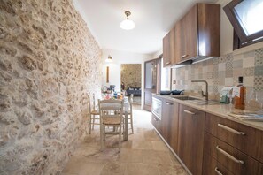 A kitchen with stone walls, wooden cabinets, and a tiled backsplash. - Corte San Giorgio Apartments with airco (Martano)