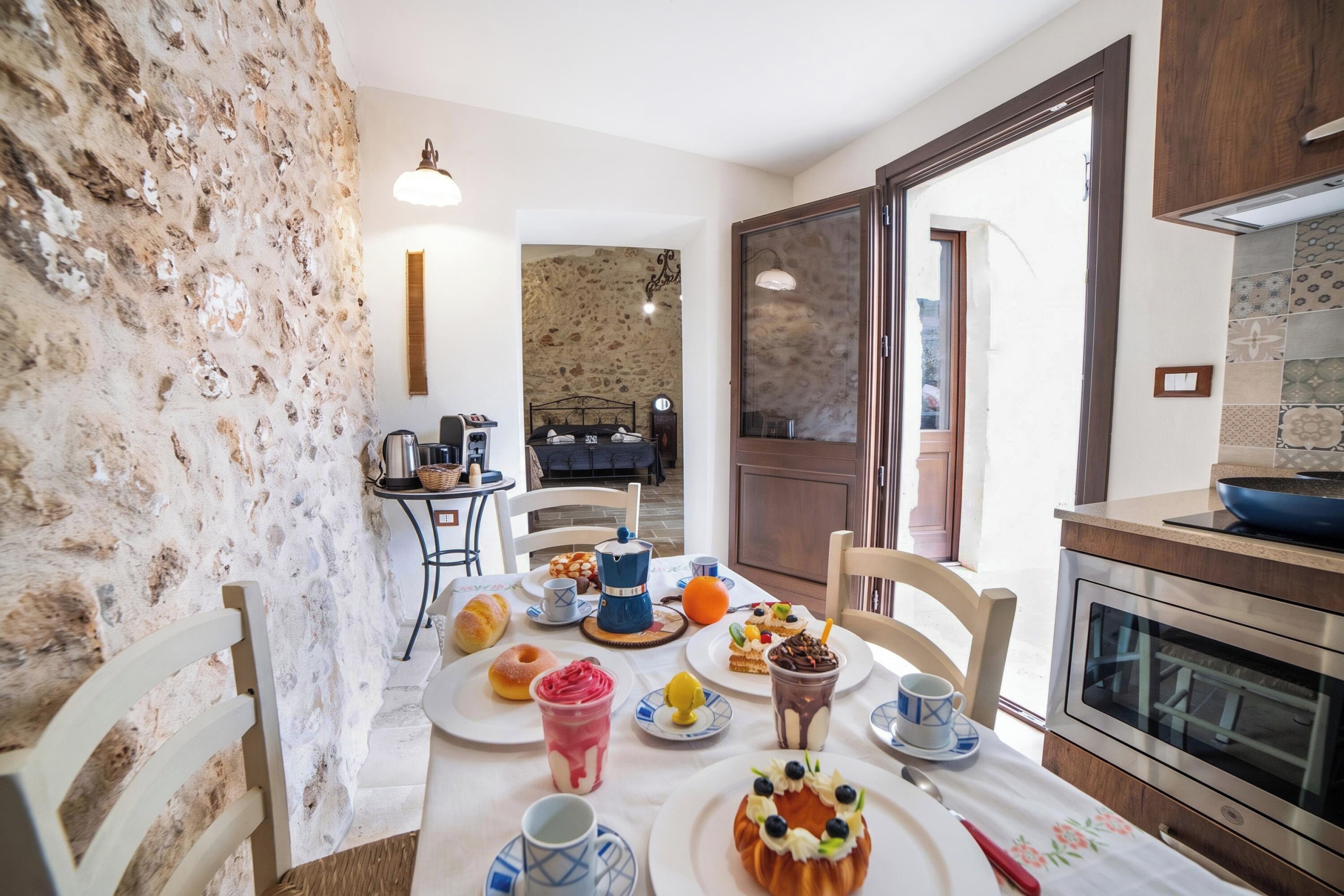 A dining area with a table set for breakfast, a coffee machine, and a view of the kitchen.
