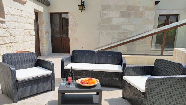 An outdoor seating area with wicker furniture and a table, a bowl of fruit, and a bottle of wine. - Corte San Giorgio Apartments with airco (Martano)