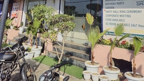 A building with a sign reading "The Royal Orchid" and a list of services including a garden, party hall, and corporate meeting space. - The Royal Orchid (Aligarh)