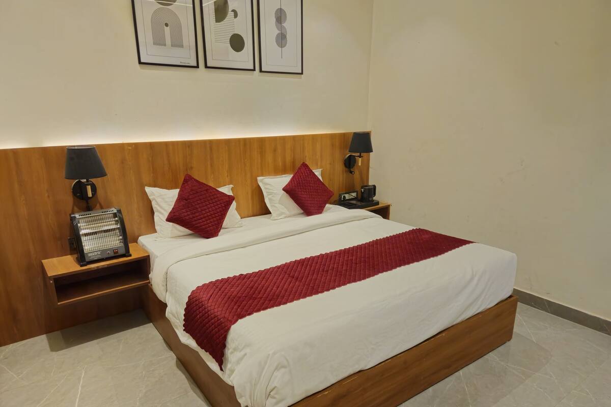 A neatly made bed with a wooden headboard, two bedside tables with lamps, and a red quilted blanket.