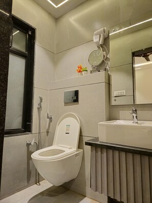 A modern bathroom with a toilet, sink, and shower. - The Royal Orchid (Aligarh)