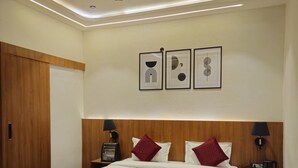 A hotel room with a wooden bed, red and white bedding, a ceiling fan, and framed artwork on the wall. - The Royal Orchid (Aligarh)