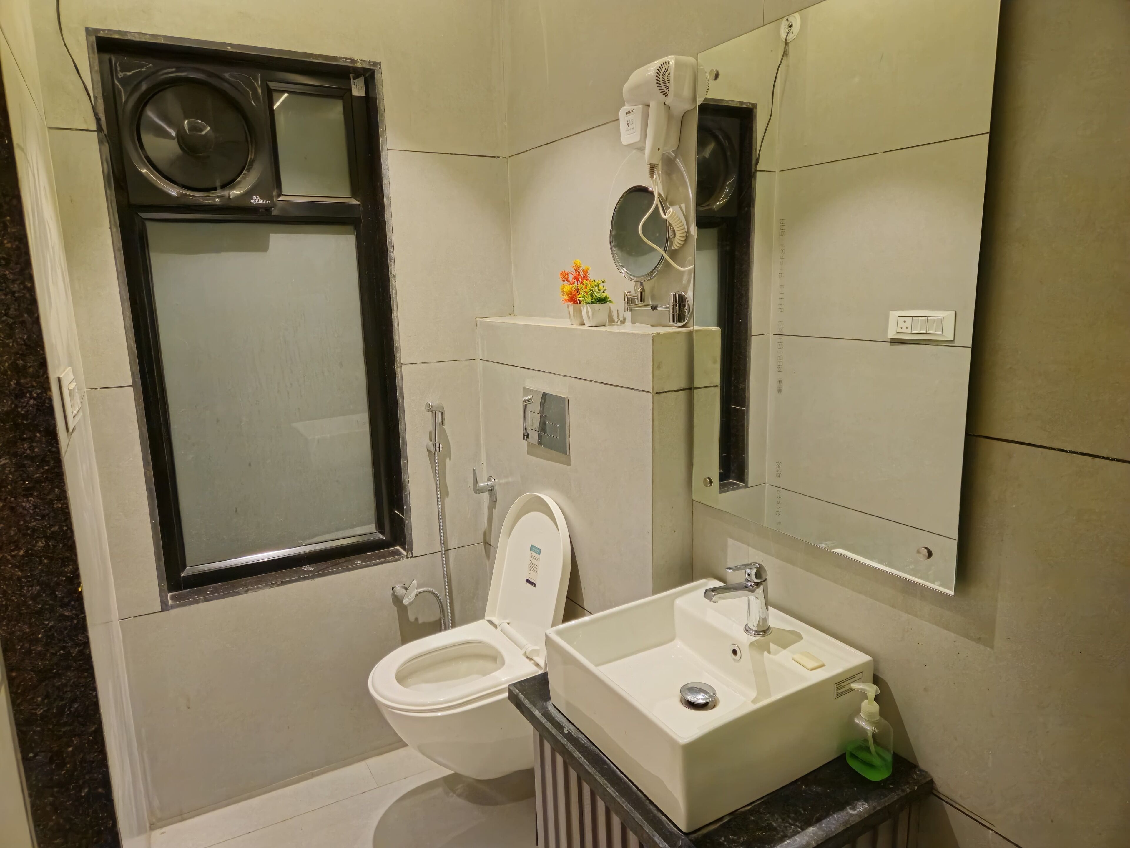 Un baño con inodoro, lavabo, espejo y ventana.