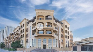 A multi-story residential building with balconies, large windows, and a central entrance. - Cozy 1 BHK with City View in JVC by AZCO (Dubai)