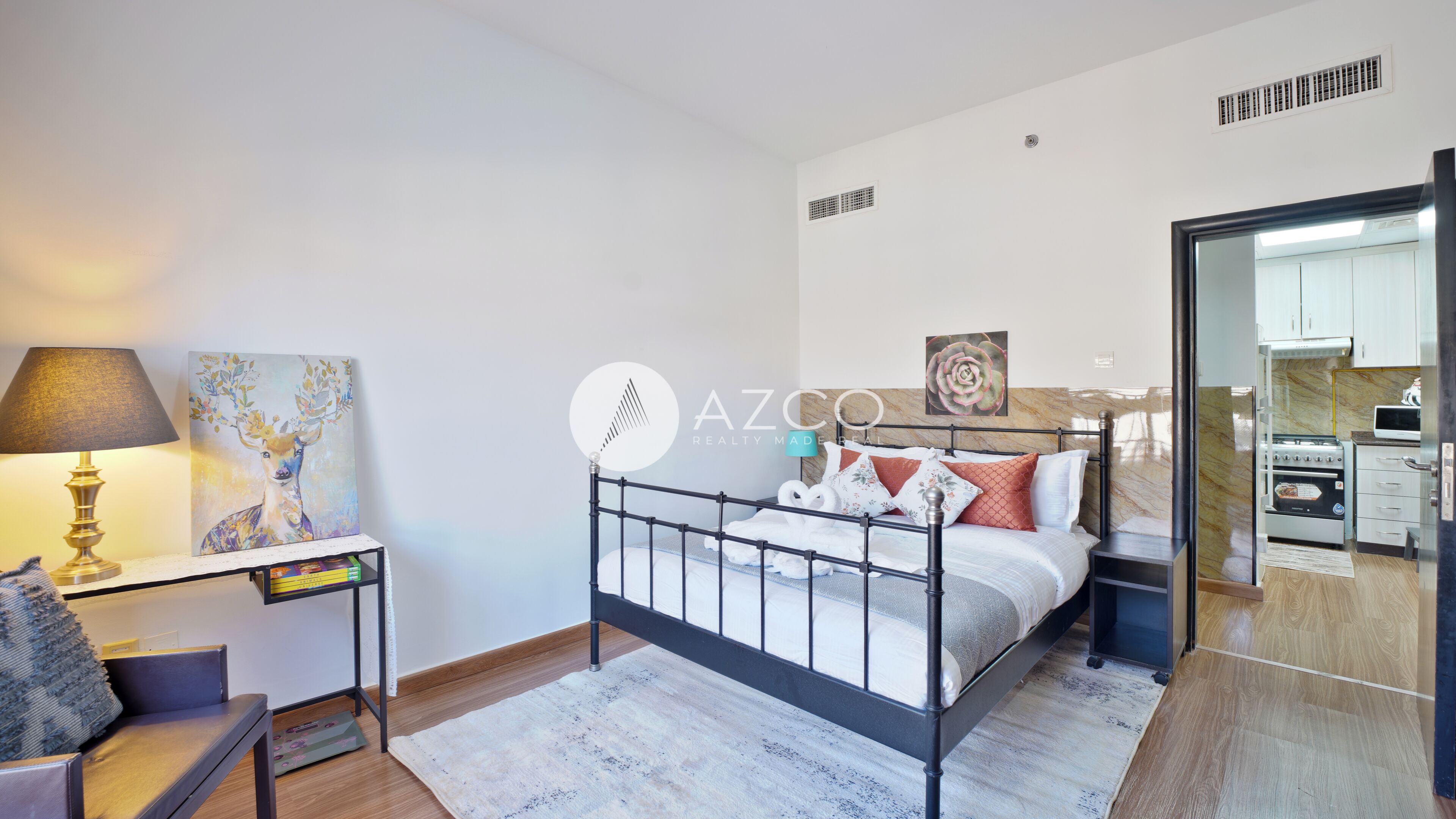 A modern bedroom with a bed, bedside table, lamp, and artwork.